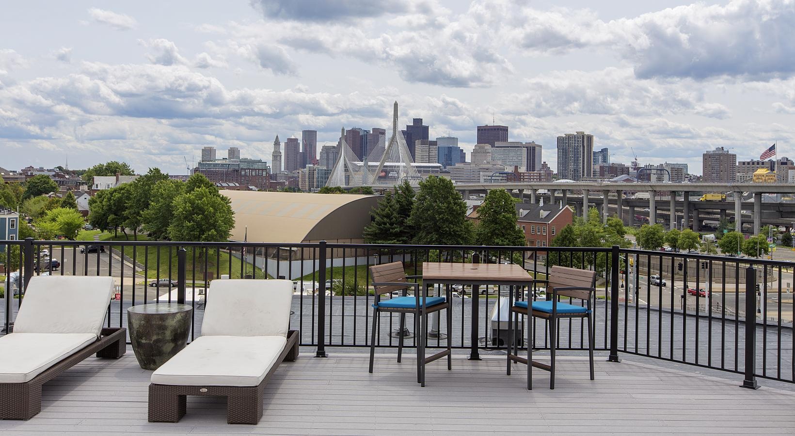 The essence of exceptional living a deck with chairs and tables and a city in the background