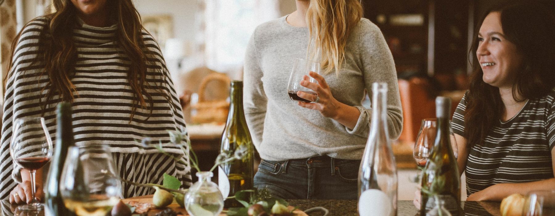 a group of women stand around a table with food