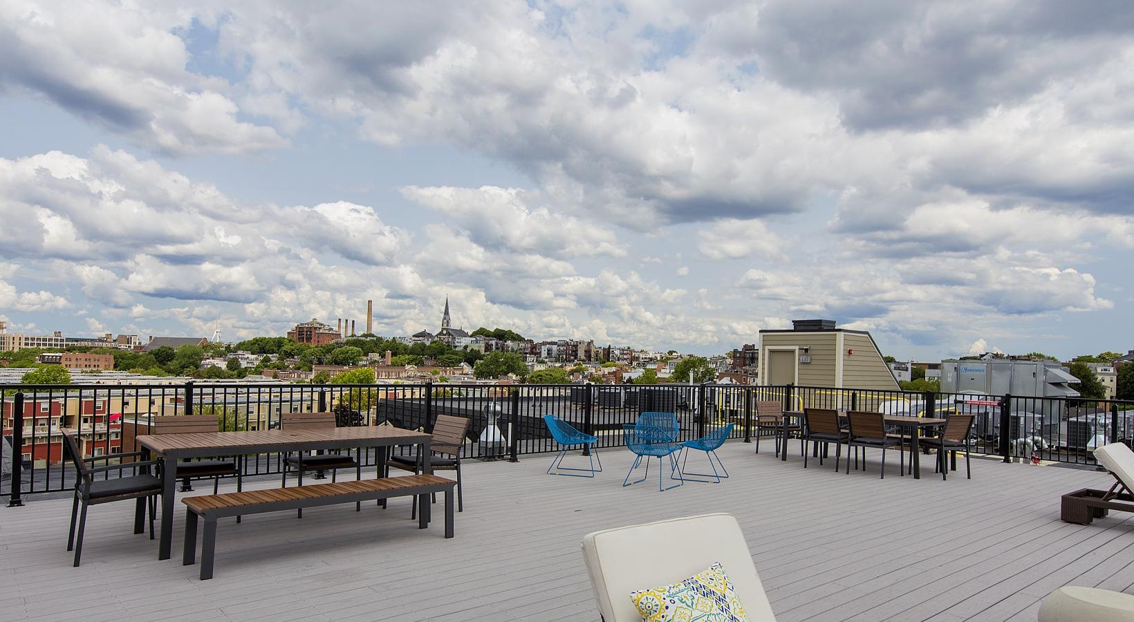 Find your perfect fit at Gatehouse 75 a deck with chairs and tables on it with a city in the background