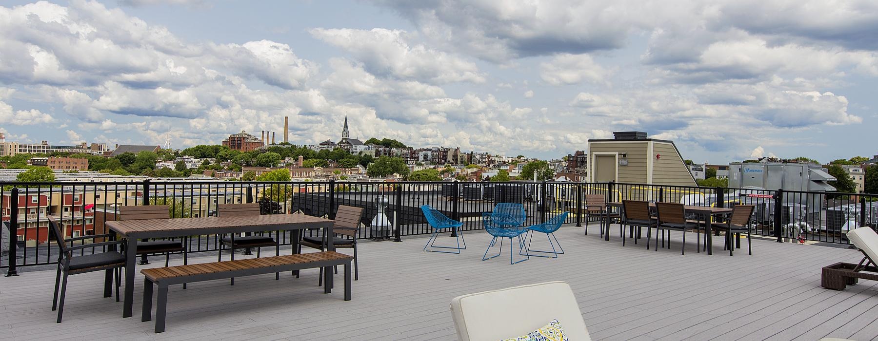 a deck with chairs and tables on it with a city in the background