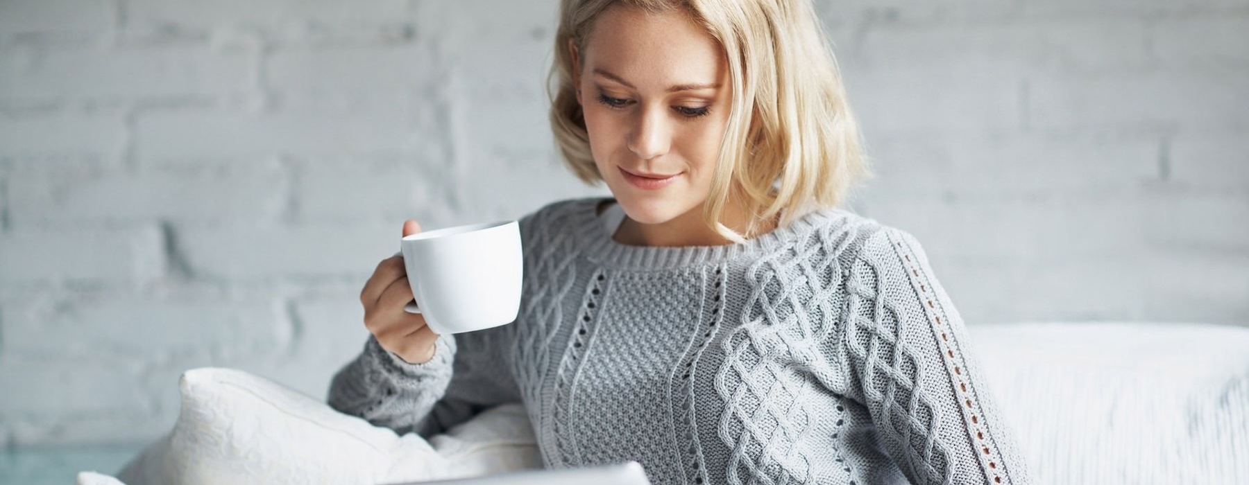 Person sitting on a couch drinking coffee